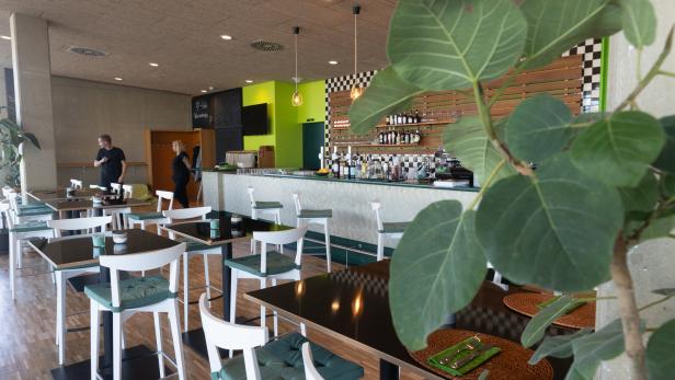 Einblick in ein modernes Restaurant mit Tischen, Stühlen und einer Bar.