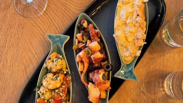 Drei Fischschalen mit Meeresfrüchtesalat auf einem Tisch angerichtet.