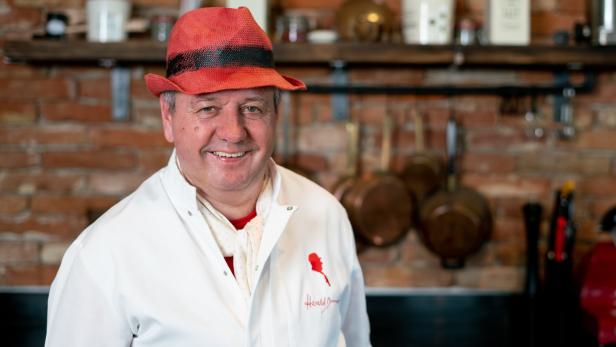 Harald Brunner mit rotem Hut lächelt in die Kamera.