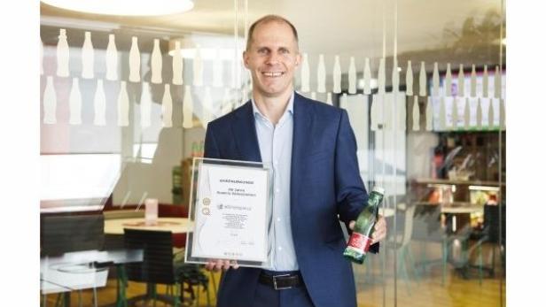 Herbert Bauer, General Manager Coca Cola HBC Österreich, mit der Ehrenurkunde über &quot;60 Jahre Austria Gütezeichen&quot; und einer Römerquelle-Flasche; Zertifizierung für Römerquelle still, prickelnd und mild.