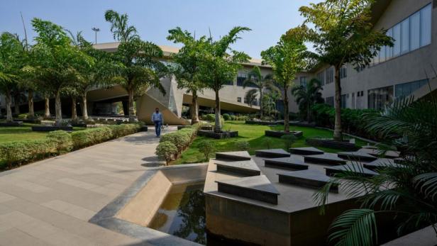 Ein Mann geht durch den begrünten Innenhof eines modernen Bürogebäudes in Indien.