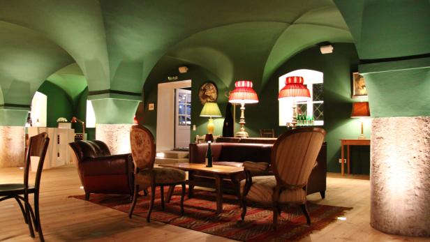 Ein Wohnzimmer mit grünen Wänden und Gewölbedecke, eingerichtet mit antiken Möbeln.