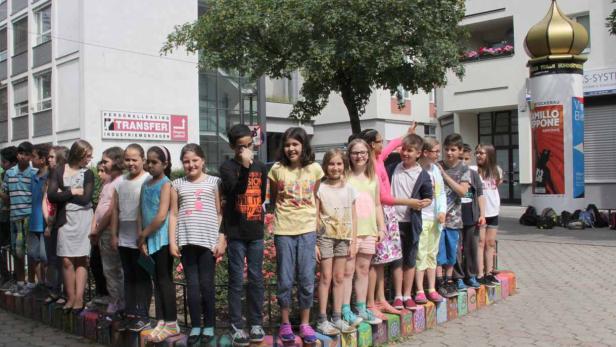 Eine Gruppe von Schulkindern steht im Freien vor einem Gebäude.