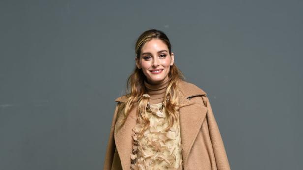 Olivia Palermo trägt einen beigen Mantel und ein Federkleid.