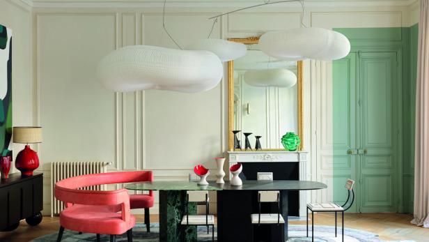 Ein Esszimmer mit einem ovalen Tisch, umgeben von Stühlen und einer skulpturalen Wolkenlampe.