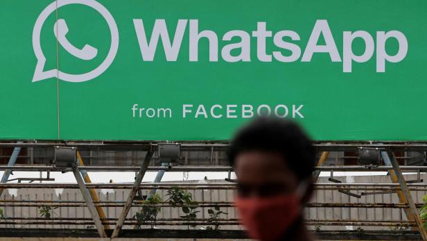 FILE PHOTO: A man walks past a hoarding of the WhatsApp application installed at a skywalk in Mumbai, India