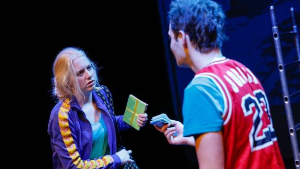 Eine Frau übergibt einem Mann in einem Sporttrikot ein Geschenk und nimmt Geld entgegen.