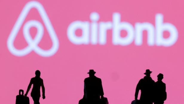 FILE PHOTO: Figurines are seen in front of displayed Airbnb logo