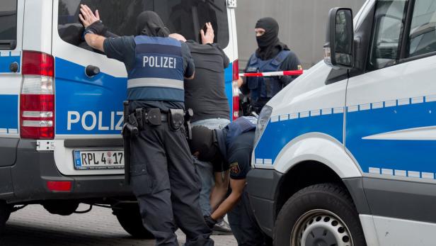 Vermummte Polizisten durchsuchen einen Mann am Flughafen Frankfurt.