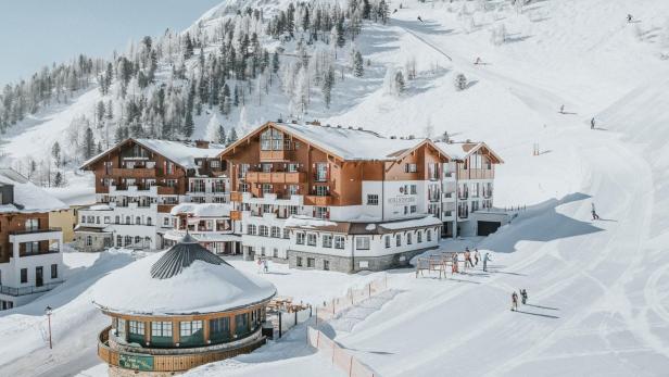 Das Hotel Schneider****Superior liegt in einer verschneiten Winterlandschaft mit Skipiste.