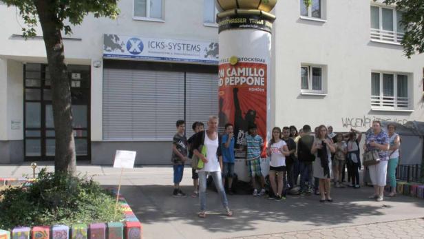 Eine Gruppe von Menschen steht vor einem Plakat für das Theaterstück „Don Camillo und Peppone“.