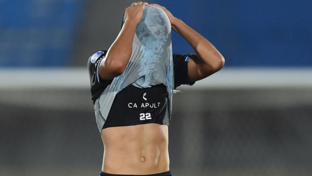 Ein Fußballspieler zieht sein Trikot über den Kopf.