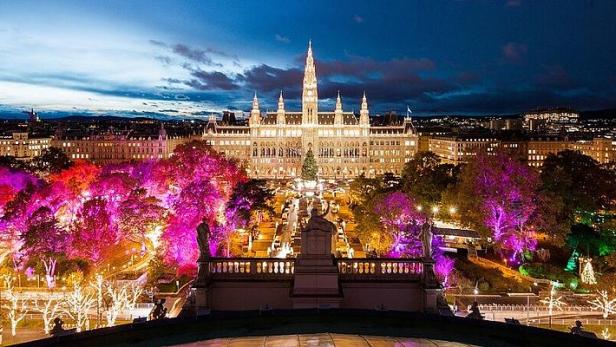 Das Wiener Rathaus und der Rathausplatz sind abends festlich beleuchtet.
