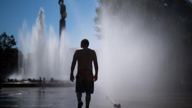 Ein Mann geht an einem heißen Tag durch einen Brunnen.