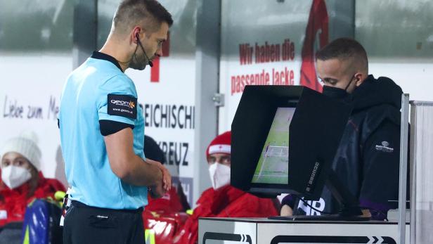 Ein Schiedsrichter steht vor einem VAR-Monitor während eines Fußballspiels.