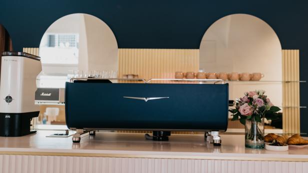 Eine blaue Espressomaschine steht auf einer Theke in einem Café.