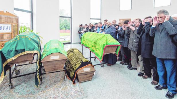Die Trauergäste beten vor den Särgen der syrischen Familie