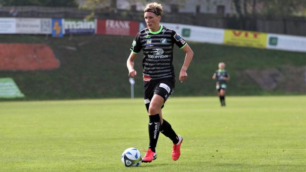 Eine Fußballspielerin dribbelt den Ball auf einem grünen Rasenplatz.