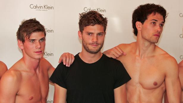 Jamie Dornan posiert mit zwei muskulösen Männern für eine Calvin Klein-Werbung.