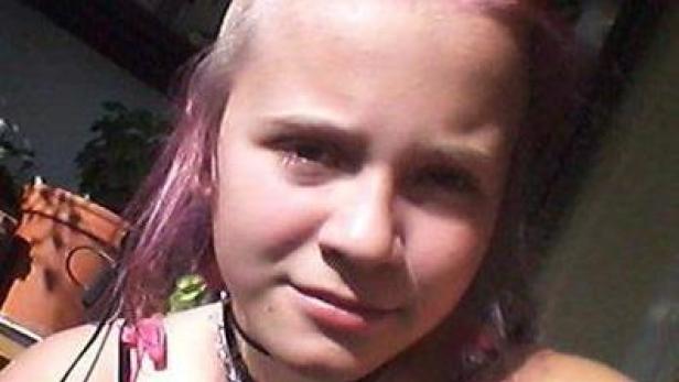 Ein Porträt einer jungen Frau mit rosa gefärbten Haaren und einem Halsband.