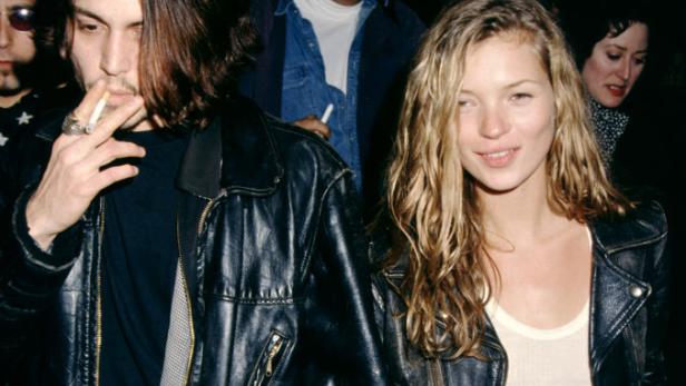 Johnny Depp und Kate Moss halten Händchen, Depp raucht eine Zigarette.