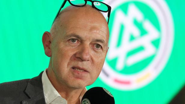 Ein Mann spricht vor einem Mikrofon mit dem DFB-Logo im Hintergrund.