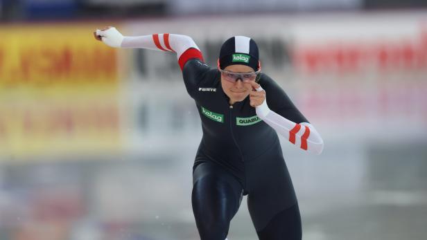 Eine Eisschnellläuferin in schwarzer Sportbekleidung und mit Brille auf dem Eis.