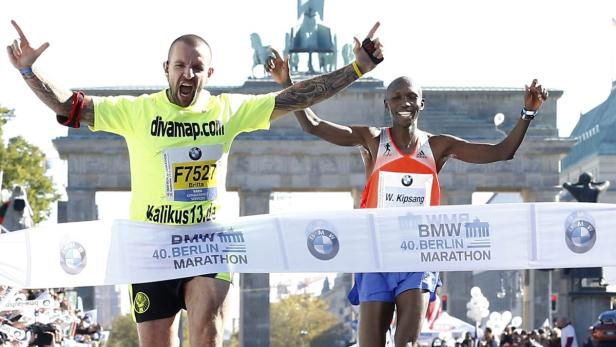 Zwei Marathonläufer überqueren die Ziellinie beim 40. Berlin-Marathon vor dem Brandenburger Tor.