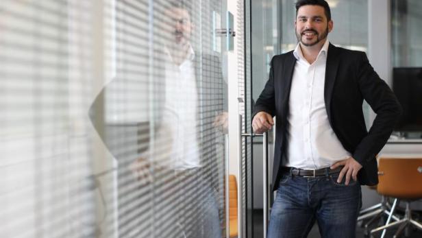 Ein Mann in Jeans und Sakko steht in einem Büro.