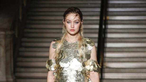 Gigi Hadid trägt ein goldenes Paillettenkleid auf einer Treppe.