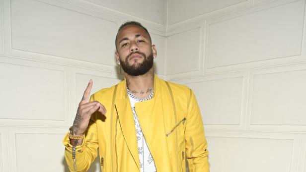 Neymar posiert in gelber Jacke, weißem Oberteil und weißen Hosen für ein Foto.