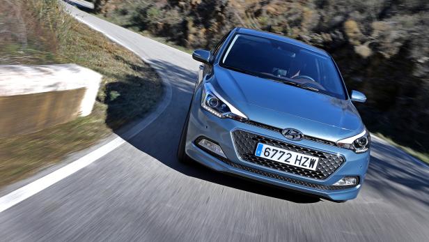 Ein blauer Hyundai fährt auf einer kurvenreichen Straße.