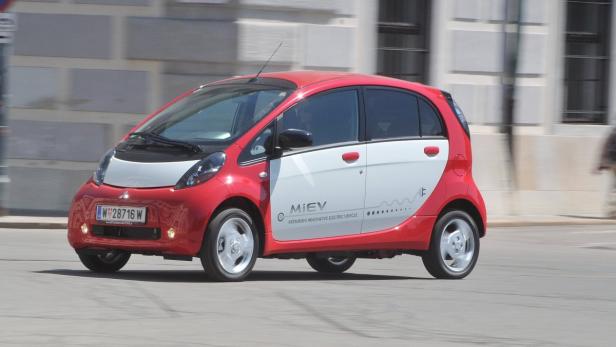 Ein roter Mitsubishi i-MiEV fährt auf einer Straße.