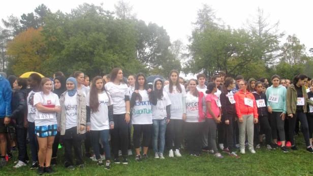 Eine Gruppe junger Menschen steht für ein Rennen bereit, viele tragen T-Shirts mit Aufschriften zum Thema Flüchtlinge.