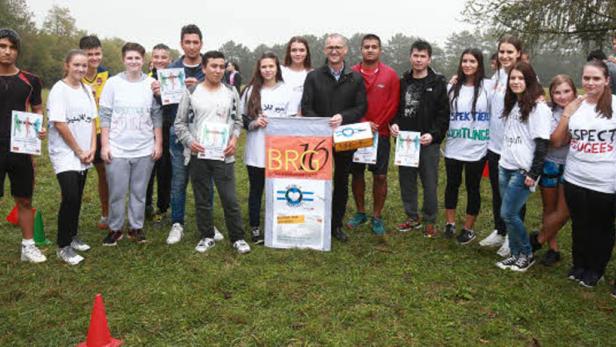 Eine Gruppe von Menschen steht auf einer Wiese und hält Schilder und Auszeichnungen.