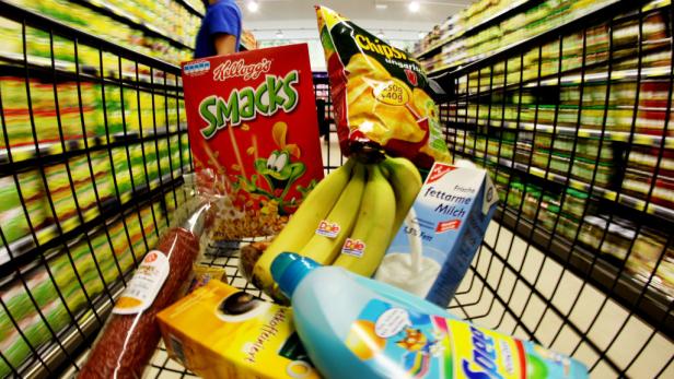 Ein Einkaufswagen gefüllt mit Lebensmitteln wie Bananen, Chips, Frühstücksflocken und Milch.