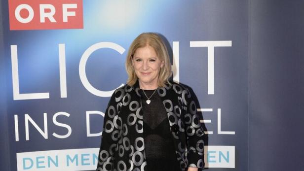Eine Frau posiert vor einem "Licht ins Dunkel"-Hintergrund des ORF.