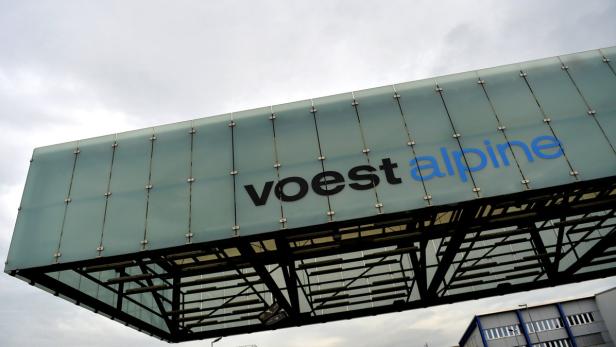 Das Voestalpine-Logo auf einem modernen Gebäude unter einem bewölkten Himmel.