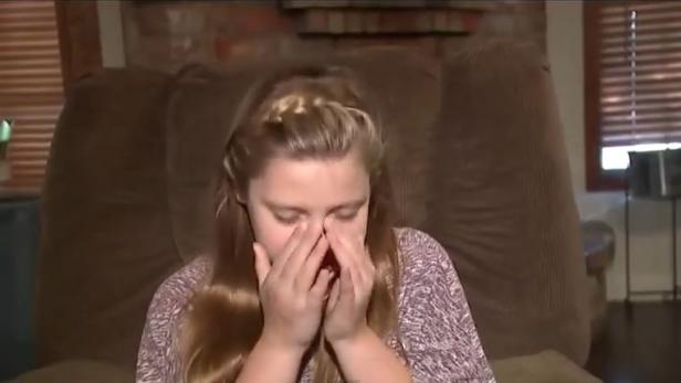 Ein junges Mädchen weint und verdeckt ihr Gesicht mit den Händen.