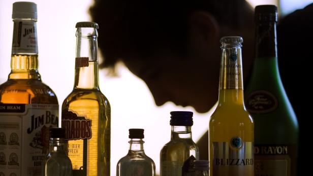ARCHIV - ILLUSTRATION - Ein Jugendlicher sitzt am 07.09.2009 hinter Flaschen mit Alkohol. 80 Prozent der deutschen Medizinabsolventen weiß nicht alko alkoholkraatienten richtig zu behandeln sind. Und dasd das, obwohl Alkoholismus eine Volkskrankheit ist: