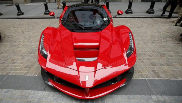 Ein roter Ferrari LaFerrari steht auf einem gepflasterten Platz.