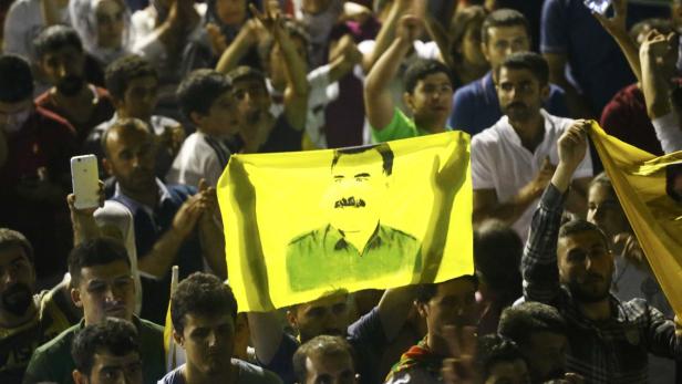 Eine Menschenmenge hält ein gelbes Tuch mit dem Bild von Saddam Hussein hoch.