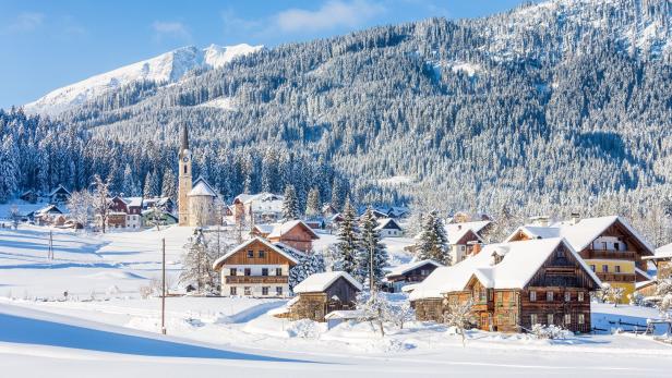 Dörfliche Winterlandschaft in Österreich, schneebedeckte Berge und Häuser