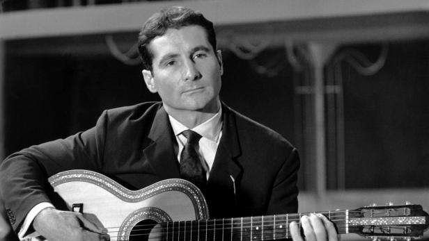 Ein Mann im Anzug spielt auf einer verzierten Gitarre.