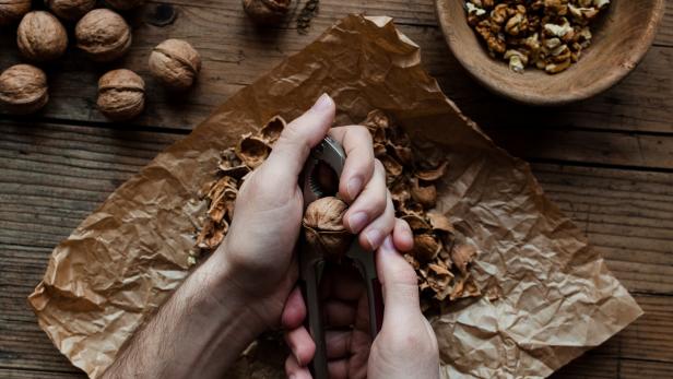 Mann knackt Walnuss.