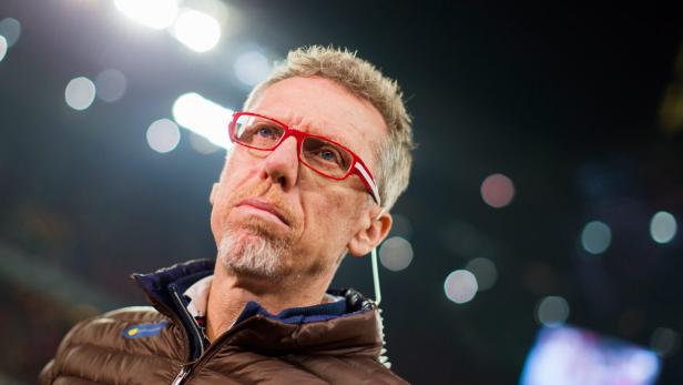 Ein Mann mit roten Brillengläsern blickt nachdenklich nach oben.