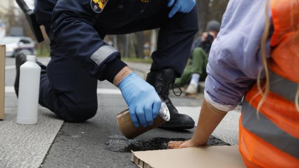 Mit einem speziellen Lösemittel entfernten die Beamten die Klimaaktivisten von der Straße.