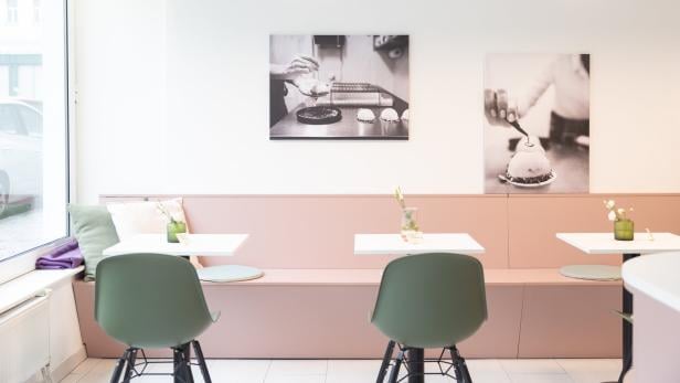 Innenansicht eines Cafés mit Tischen, Stühlen und Schwarz-Weiß-Fotografien an der Wand.