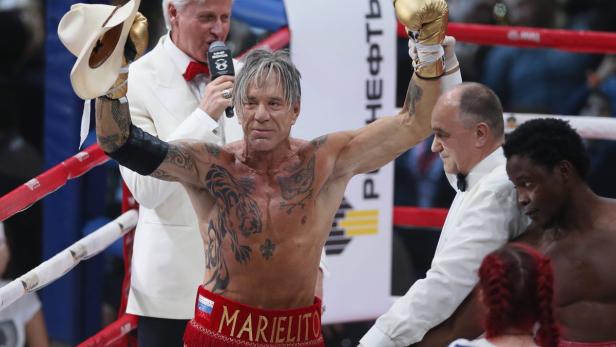 Mickey Rourke feiert seinen Sieg in einem Boxkampf mit erhobenen Armen.
