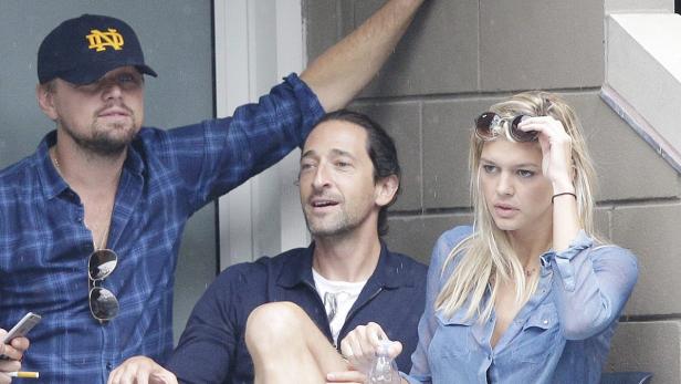 Leonardo DiCaprio, Adrien Brody und eine blonde Frau sitzen zusammen im Freien.